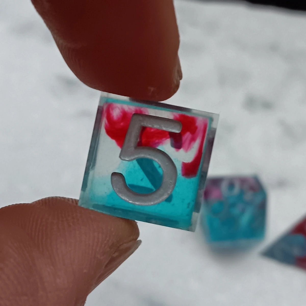 d6 with silver numbers. Die is split between translucent light blue and clear with a red swirl. 